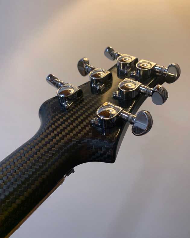 back of a carbon fibre guitar headstock with chrome tuners